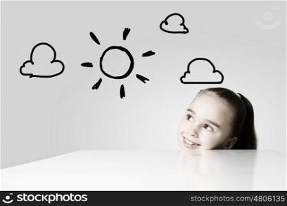 Happy childhood. Little cute girl looking at drawing of sun