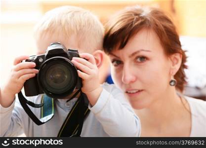 Happy childhood. Mother and her son boy child kid playing with camera taking photo. At home. Real.