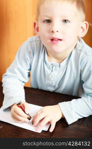 Happy childhood. Portrait of blond boy child kid drawing with marker picture on piece of paper. At home.