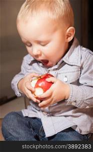 Happy childhood. Portrait of cute little boy child kid eating apple fruit at home. Healthy diet and nutrition.