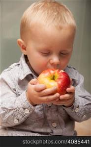 Happy childhood. Portrait of cute little boy child kid eating apple fruit at home. Healthy diet and nutrition.
