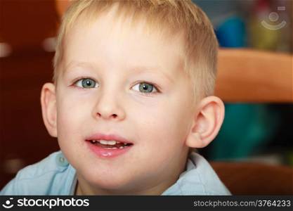 Happy childhood. Portrait of happy smiling blond boy child kid preschooler sitting on chair. Indoor.