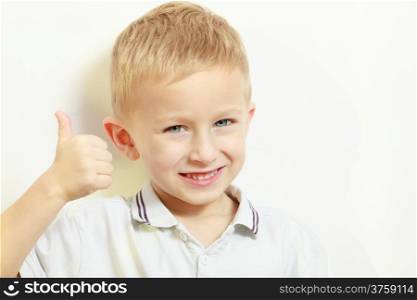 Happy childhood. Portrait of smiling blond boy child kid preschooler showing thumb up success hand sign gesture. Indoor.
