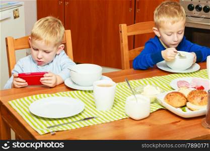Happy childhood.Two blond brothers boys kids children eating corn flakes breakfast morning meal at the table. Home.