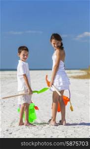 Happy children, boy girl, brother and sister having fun playing in the sand on a beach with bucket and spade