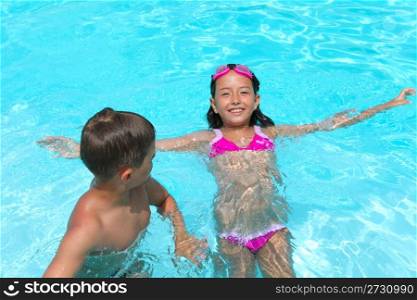 Happy children, girl and boy, relaxing on the side of a swimming pool wearing pink and grey goggles