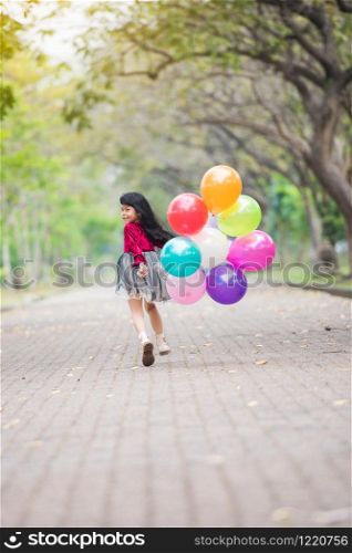 Happy children girl red cloth smile and running with balloons colorful at park holiday
