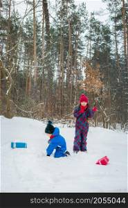 Happy children in a winter snow-covered forest with gift boxes. Christmas fun for Christmas and New Year.. Happy children in a winter snow-covered forest with gift boxes.