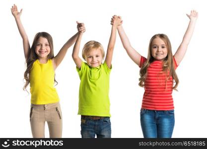Happy children isolated on white. Happy smiling three children in colorful clothes holding raised hands isolated on white background