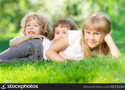 Happy children lying on green grass in spring park