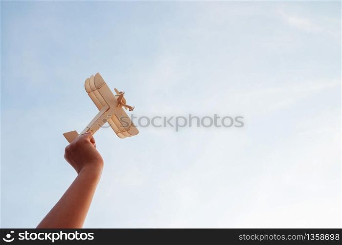 Happy children playing a wooden toy plane On the sunset sky background