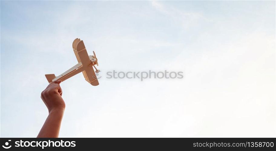 Happy children playing a wooden toy plane On the sunset sky background