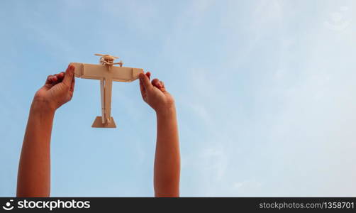 Happy children playing a wooden toy plane On the sunset sky background