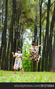 Happy children playing on the green grass in the spring garden. Two little sisters are running on a meadow in a summer park.