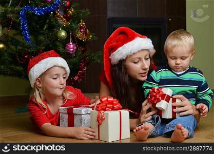 happy children with mother sitting near Christmas tree