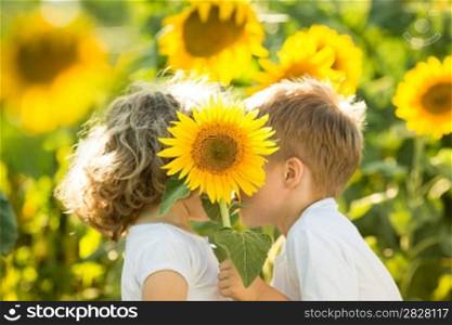 Happy children with sunflower playing in spring field