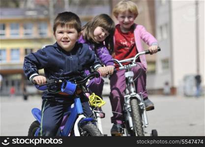 happy childrens group learning to drive bicycle outdoor at beautiful sunny spring day
