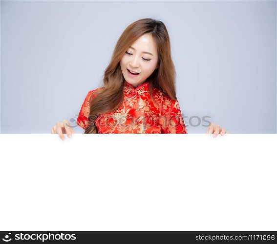 Happy Chinese New Year beautiful portrait young asian woman cheongsam dress holding board isolated on white background, girl smile and presenting showing banner copy space billboard, holiday concept.