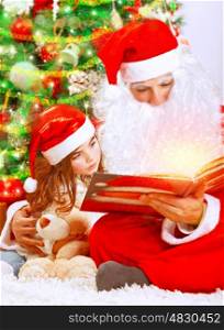 Happy Christmas eve at home, cute little girl sitting near beautiful xmas tree and reading magic book with Santa Claus, enjoying winter holidays concept