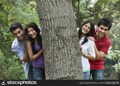 Happy college students behind tree