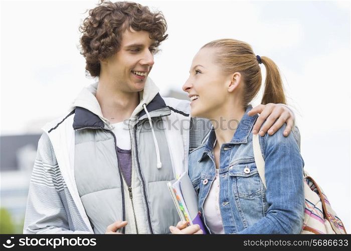 Happy college students looking at each other at campus
