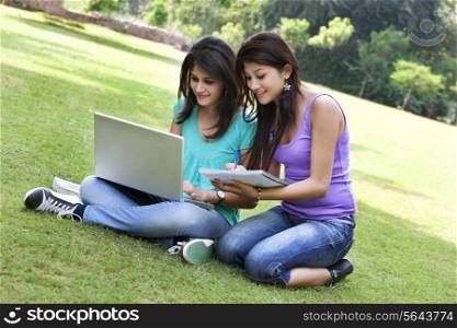 Happy college students taking notes from laptop