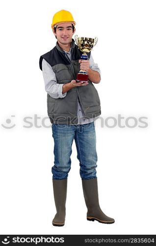 Happy construction worker holding golden cup
