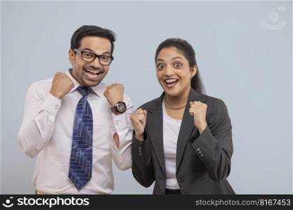 Happy corporate couple cheering with raising their fists