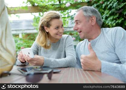 happy couple at coffee shop using smartphone