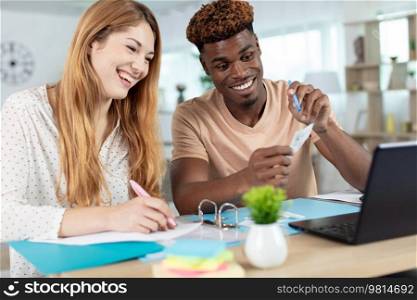 happy couple at home paying bills with laptop