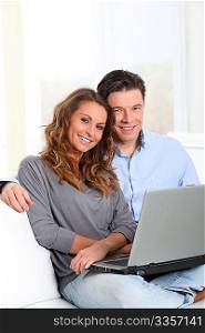 Happy couple at home with laptop computer