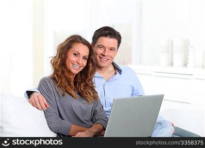 Happy couple at home with laptop computer