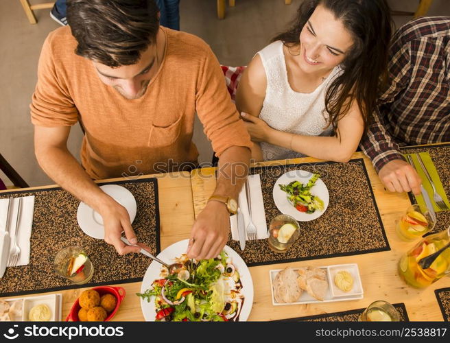 Happy couple at the restaurant and being served of food in the plate