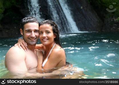 Happy couple bathing near waterfall in island