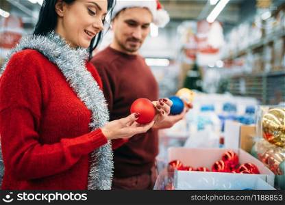 Happy couple chooses christmas tree balls in supermarket, family tradition. December shopping of holiday goods