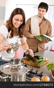 Happy couple cook together in modern kitchen with cookbook