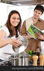 Happy couple cook together in modern kitchen with cookbook