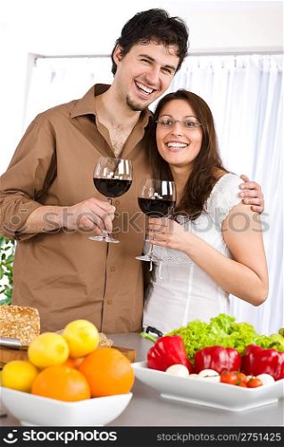 Happy couple drink red wine in modern kitchen together