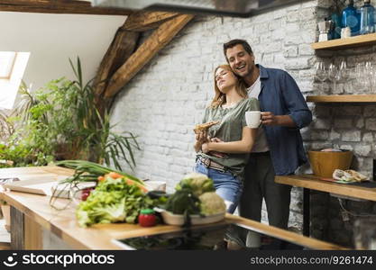 Happy couple eating breakfast together in the rustic kitchen at home