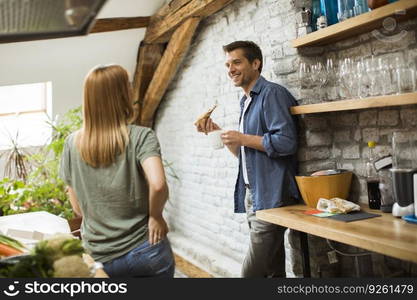 Happy couple eating breakfast together in the rustic kitchen at home