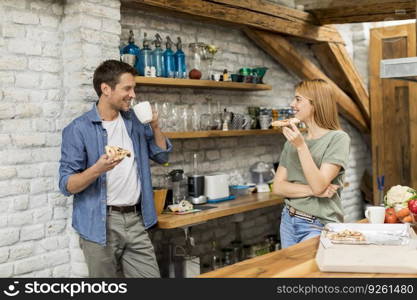 Happy couple eating breakfast together in the rustic kitchen at home