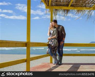Happy couple enyojing time together on beach during autumn day. Couple chating and having fun at beach bar