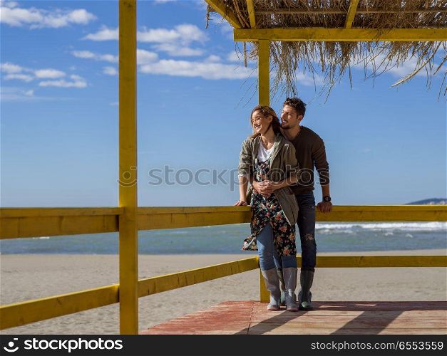 Happy couple enyojing time together on beach during autumn day. Couple chating and having fun at beach bar