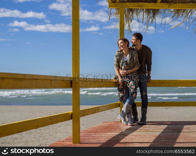 Happy couple enyojing time together on beach during autumn day. Couple chating and having fun at beach bar