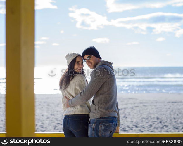 Happy couple enyojing time together on beach during autumn day. Couple chating and having fun at beach bar