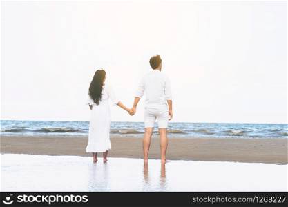 Happy couple going honeymoon travel on tropical sand beach in summer.