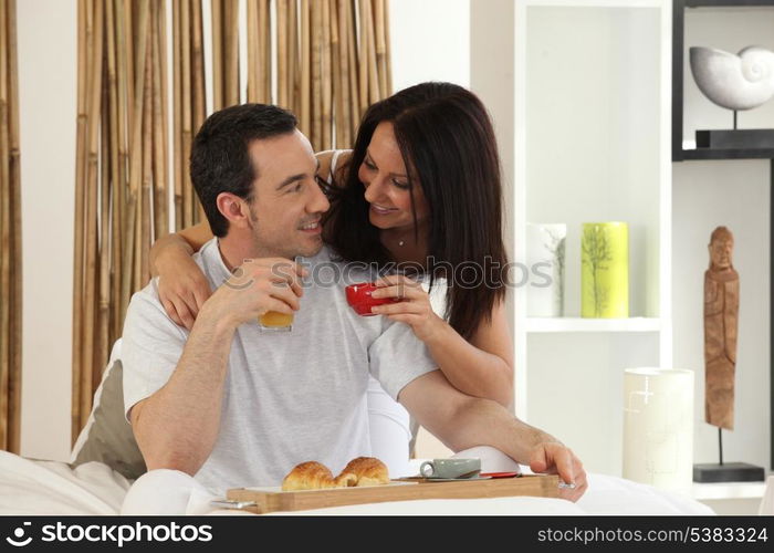 happy couple having breakfast in bed