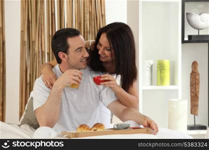 happy couple having breakfast in bed