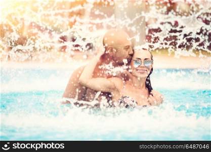 Happy couple having fun in the pool, joyful family with pleasure spending summer holidays on the beach resort, romantic honeymoon vacation. Happy couple in the pool