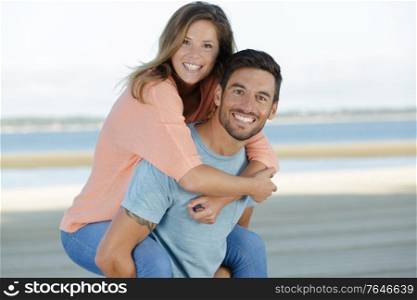 happy couple having fun while piggybacking in the sea
